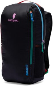 Cotopaxi Batac 16L Backpack in black with colorful zippers and a pink Cotopaxi logo. The backpack features multiple pockets, including mesh side pockets, and is designed for lightweight, versatile use.