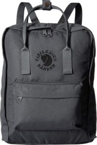 A dark gray Fjällräven Re-Kånken backpack, one of the best eco-friendly school bags for 2024, is shown from the front. It features a signature square shape with rounded edges, sturdy top handles, adjustable shoulder straps, and a front zippered pocket. The brand's logo, a curled fox, is embroidered in black on the front pocket, emphasizing the backpack's minimalist, durable, and eco-friendly design.