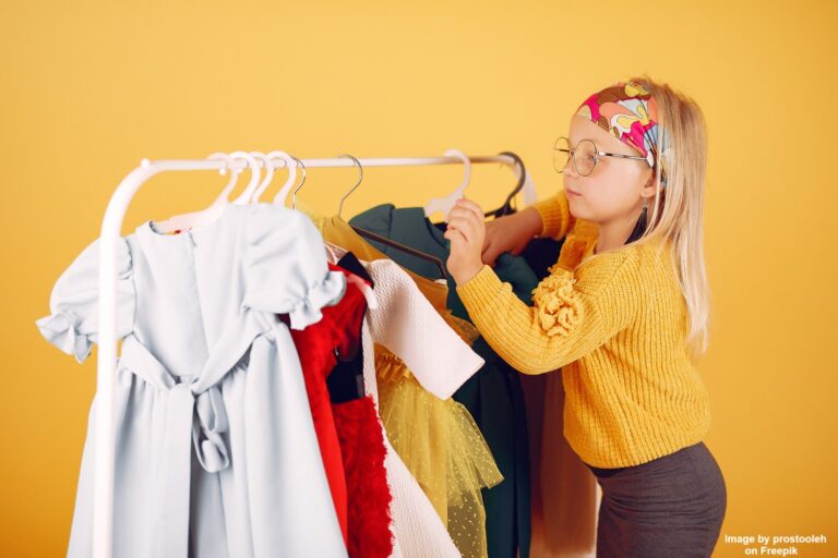 A young girl selecting clothes from a clothing rack filled with colorful, sustainable kids' outfits, illustrating the idea of building a versatile and eco-friendly wardrobe.