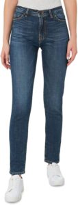 Model wearing Outland Denim Women's Lucy jeans—mid-rise skinny fit in dark blue wash, made from organic cotton, paired with a grey top and white sneakers, standing against a white background.