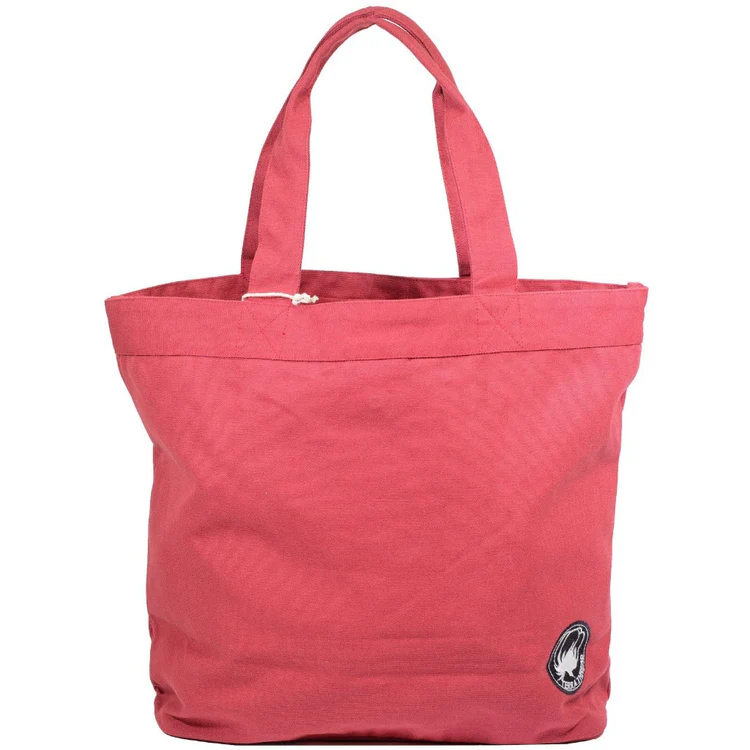 Eco-friendly beach tote resting on sand with summer essentials like sunglasses, a book, and reef-safe sunscreen