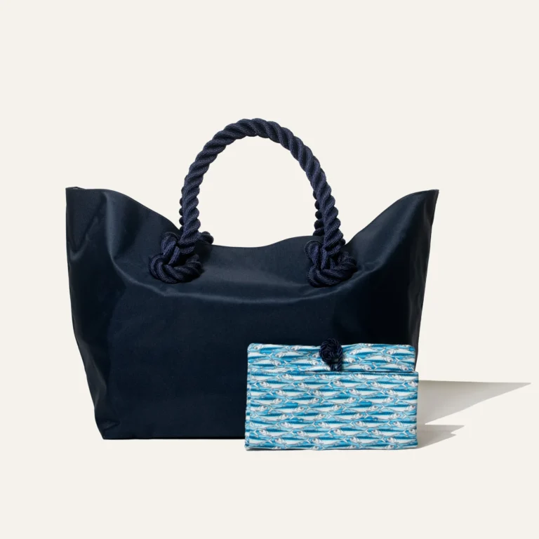 Eco-friendly beach bag by Kampos made from recycled ocean plastic, featuring navy blue design, rope handles, and matching sardine-print pouch.